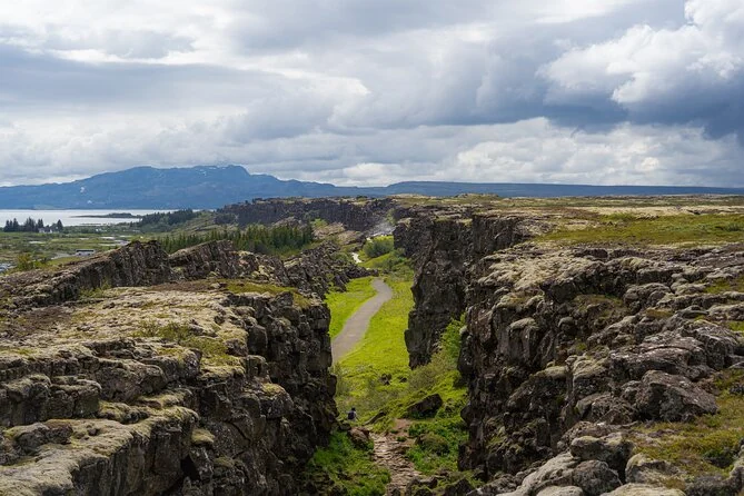 Ein Pfad entlang eines felsigen Grabenbruchs in Þingvellir unter bewölktem Himmel
